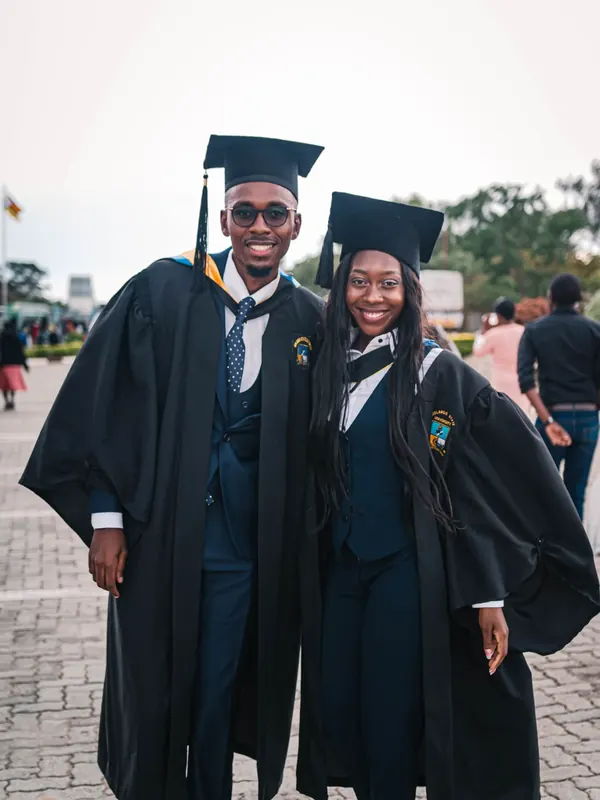 Two smiling young African graduates in gowns on graduation day